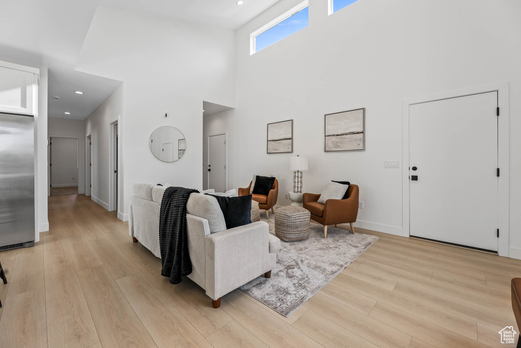 Living area featuring light wood-type flooring, recessed lighting, and a towering ceiling