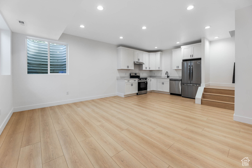 Kitchen featuring stainless steel appliances, light wood-style flooring, white cabinetry, recessed lighting, and under cabinet range hood