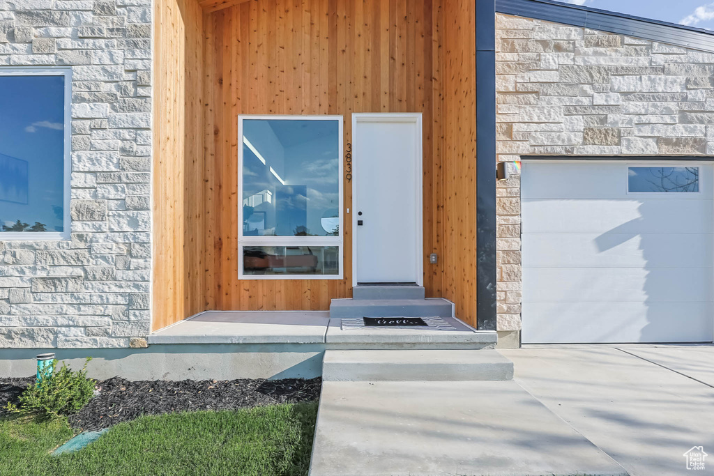 Entrance to property with stone siding and a garage