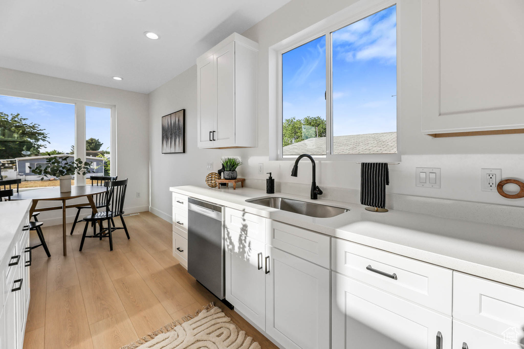Kitchen with dishwasher, light countertops, recessed lighting, light wood finished floors, and white cabinets