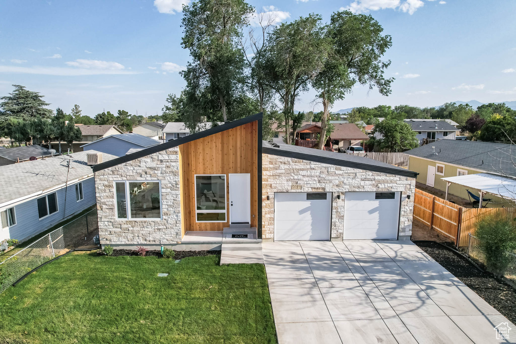 View of front of house featuring stone siding, driveway, a garage, and a residential view