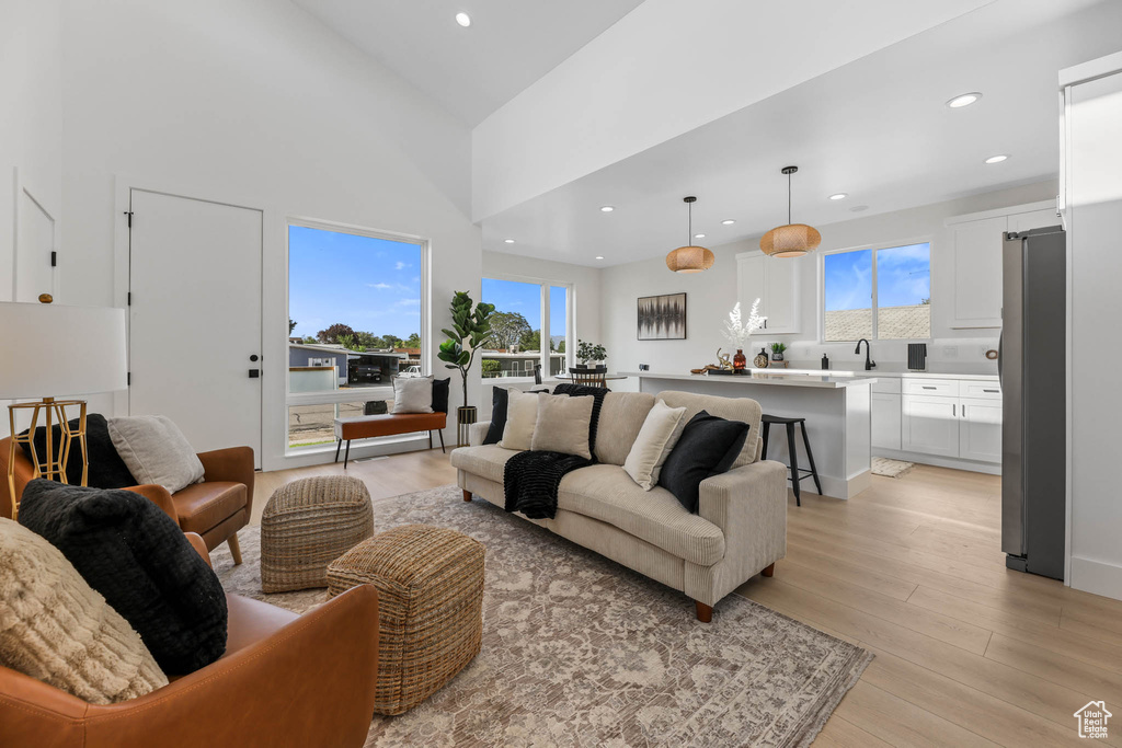 Living area featuring light wood-style flooring, healthy amount of natural light, recessed lighting, and lofted ceiling