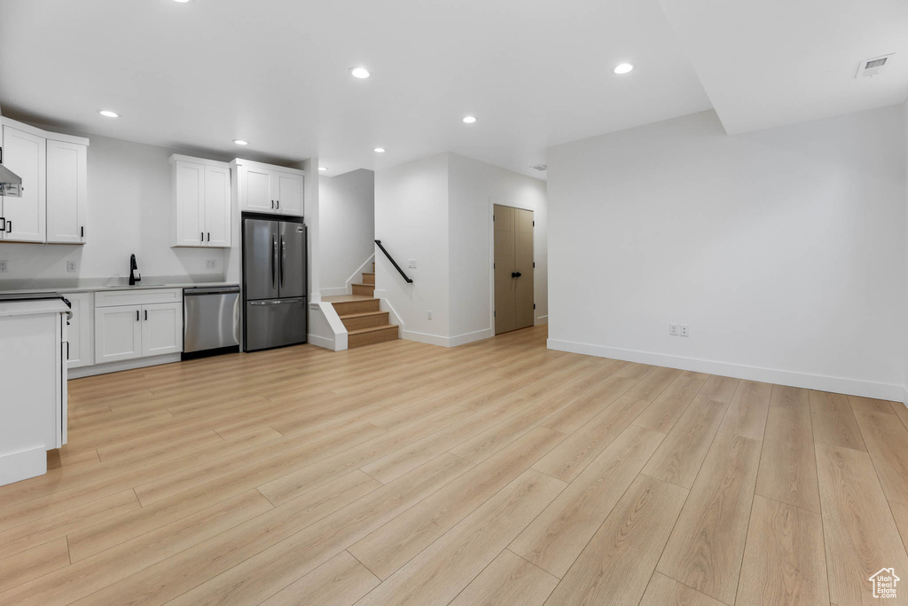 Unfurnished living room featuring recessed lighting, stairway, and light wood finished floors