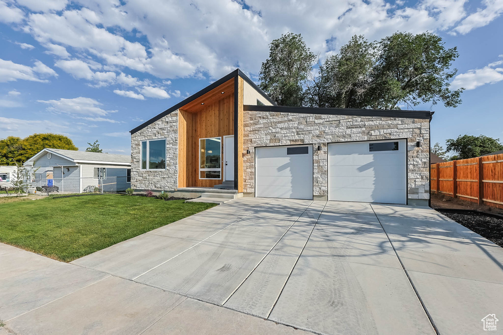 Contemporary house featuring stone siding, concrete driveway, and an attached garage
