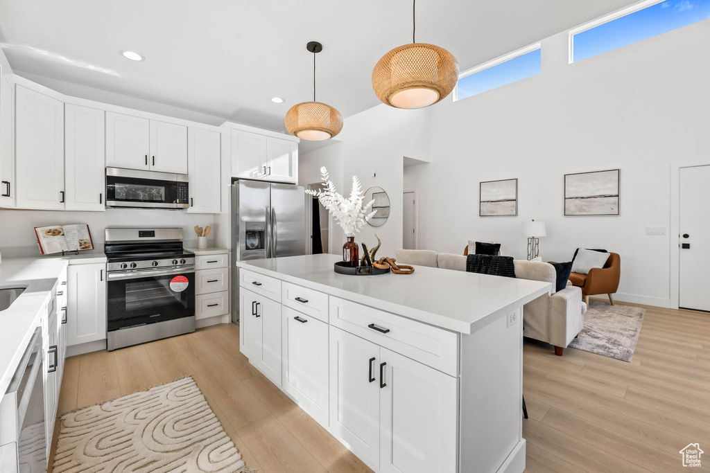 Kitchen with stainless steel appliances, recessed lighting, light countertops, light wood-style flooring, and white cabinets