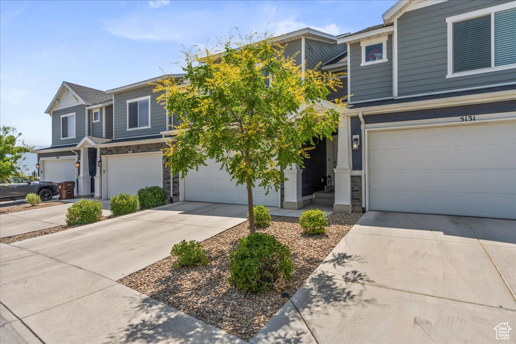 View of front of house with concrete driveway, an attached garage, and stone siding