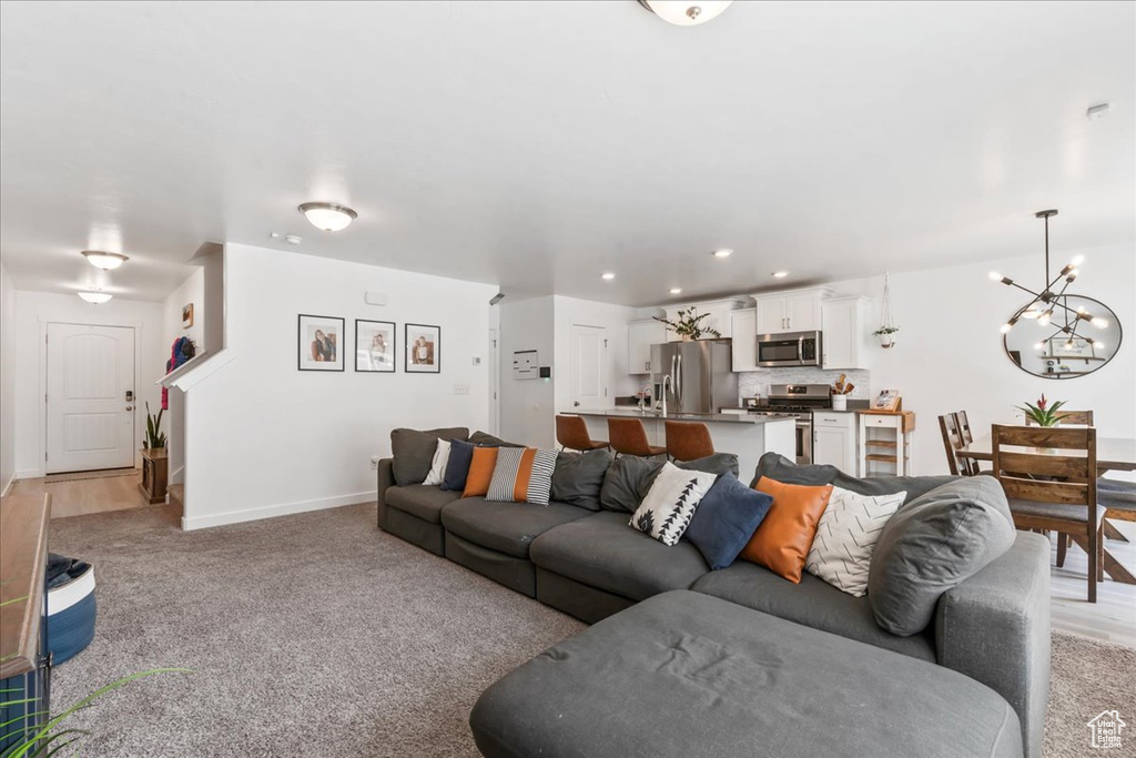 Living area with a chandelier, recessed lighting, and light carpet