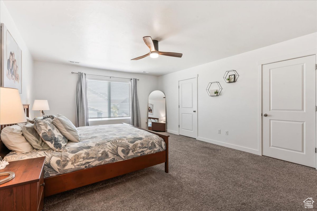 Carpeted bedroom with ceiling fan and arched walkways