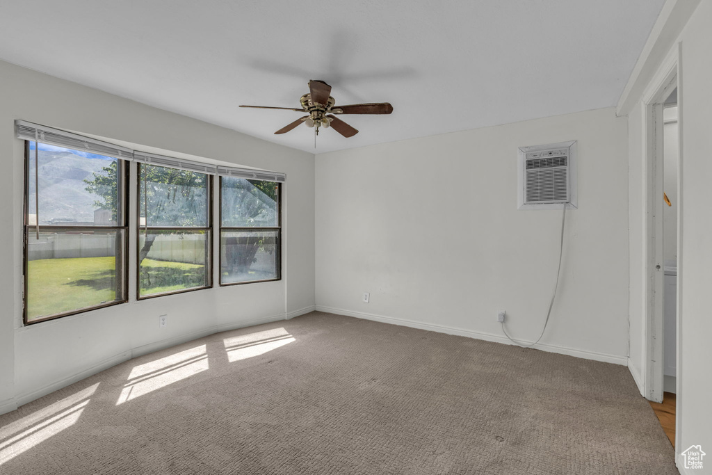 Carpeted empty room with ceiling fan and a wall mounted air conditioner