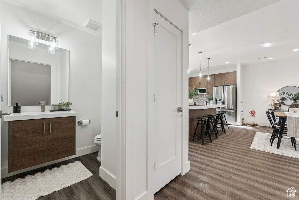 Full bath with vanity, wood finished floors, and recessed lighting