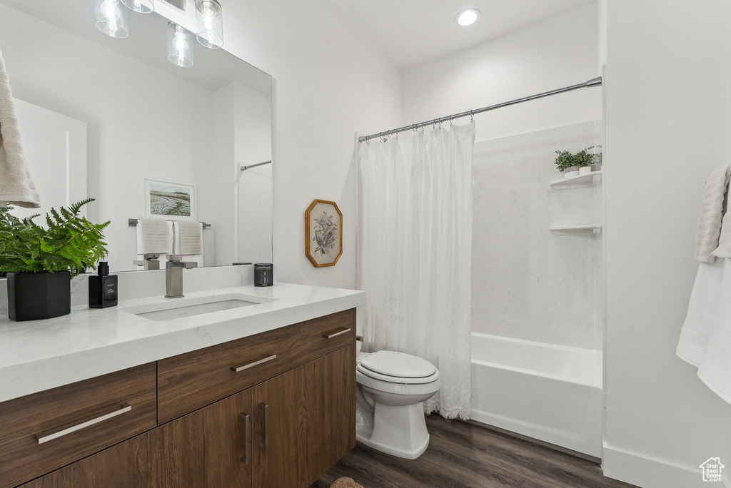 Full bath with wood finished floors, vanity, shower / tub combo, and recessed lighting