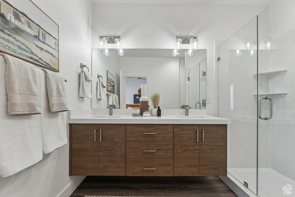 Bathroom featuring double vanity, wood finished floors, and a stall shower