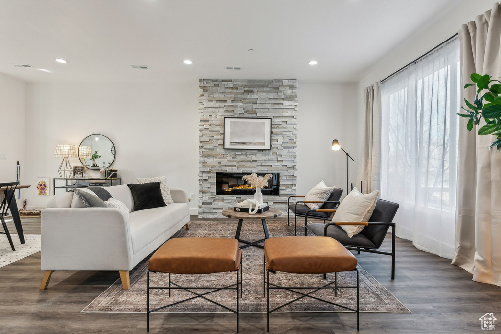 Living room with wood finished floors, a stone fireplace, and recessed lighting