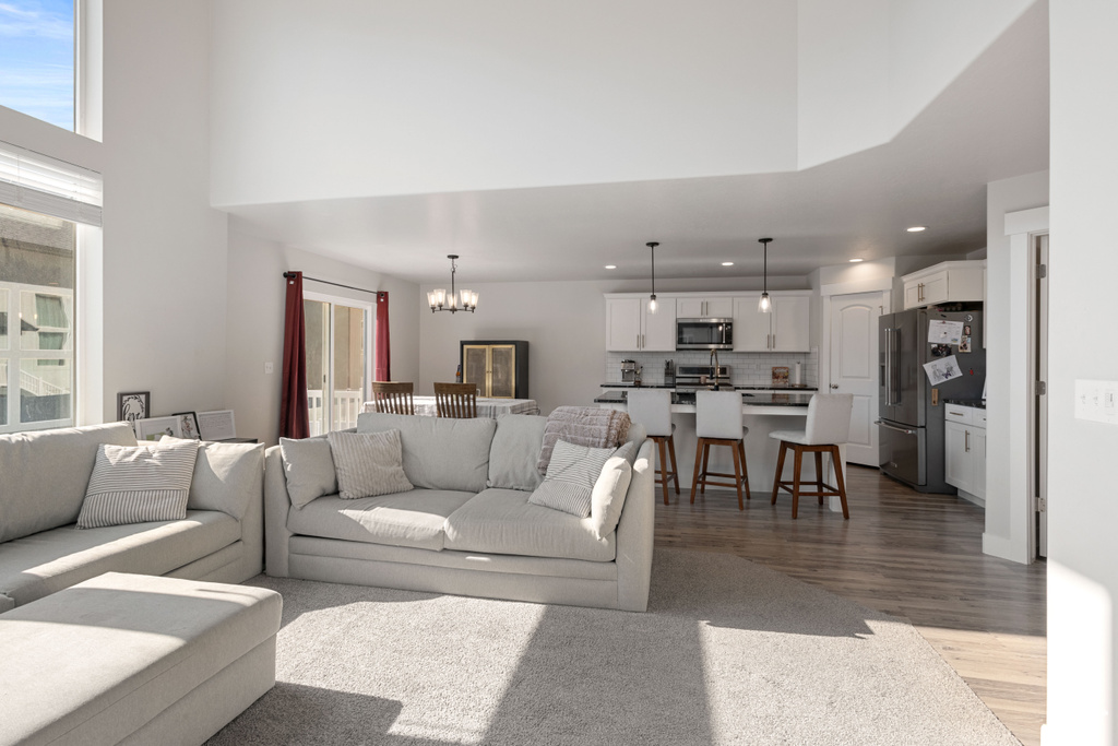 Living room with a chandelier, wood finished floors, recessed lighting, and a high ceiling