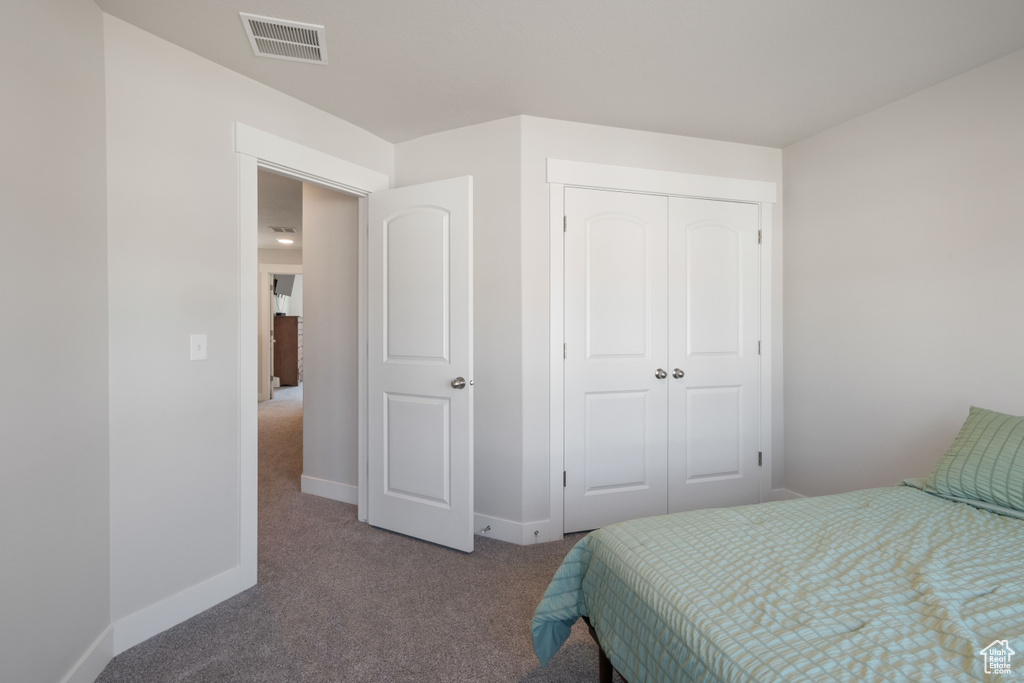 Carpeted bedroom with a closet and baseboards