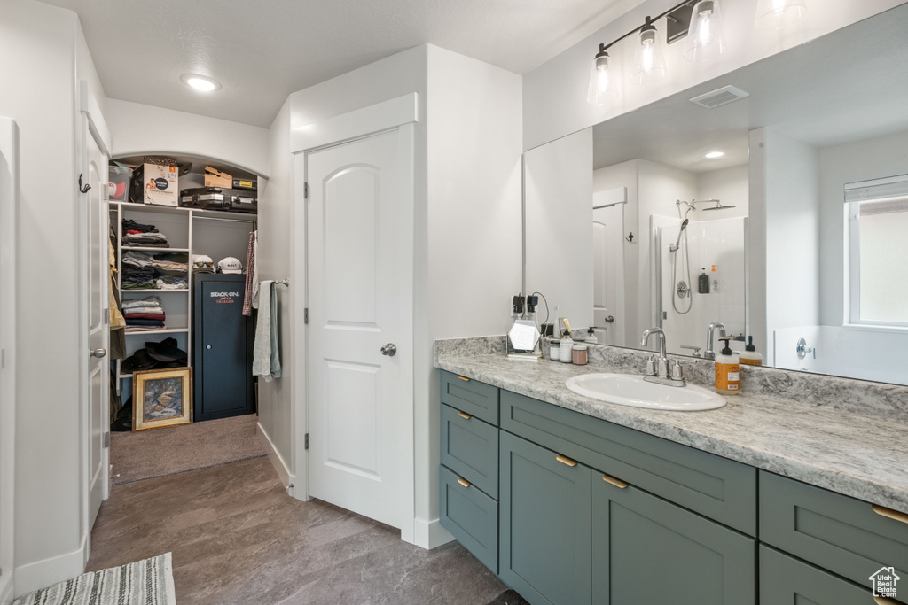 Bathroom with a shower stall, vanity, and a spacious closet