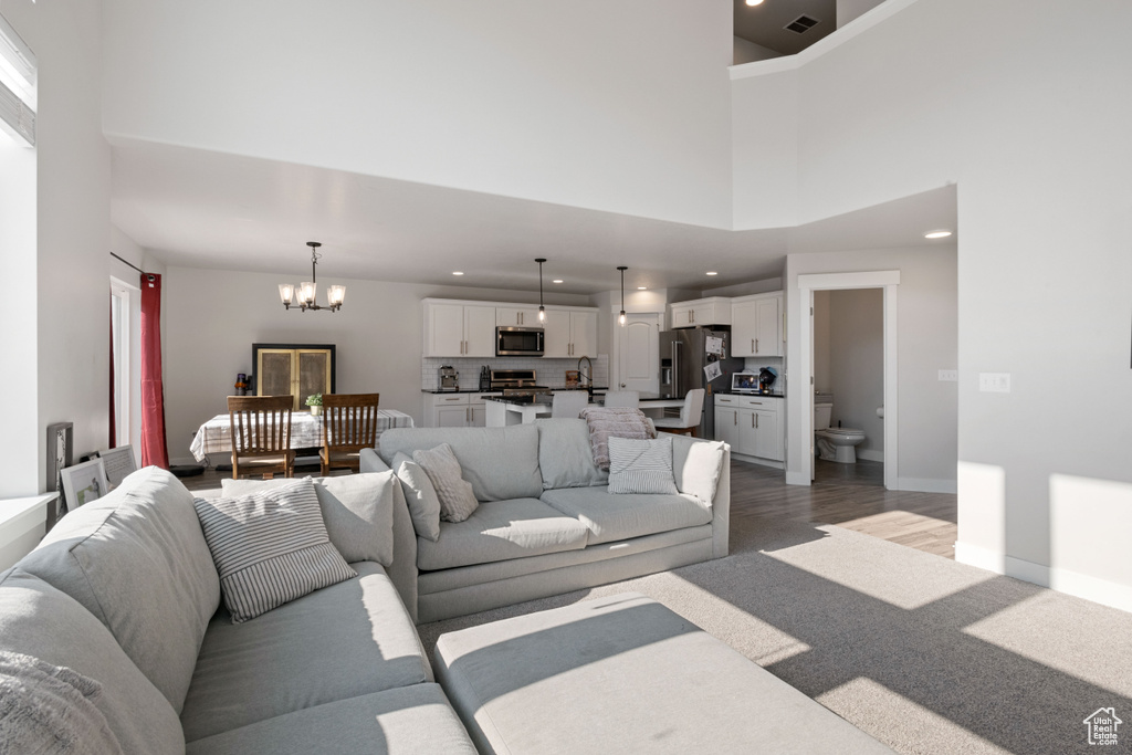 Living area with a chandelier, a high ceiling, wood finished floors, and recessed lighting