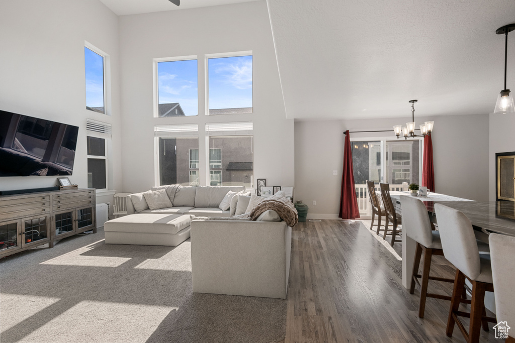 Living area with a chandelier, healthy amount of natural light, a high ceiling, and wood finished floors