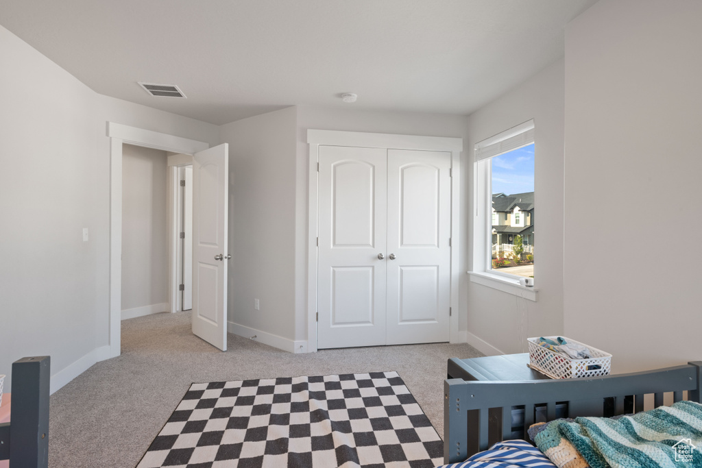 Bedroom featuring light colored carpet and a closet