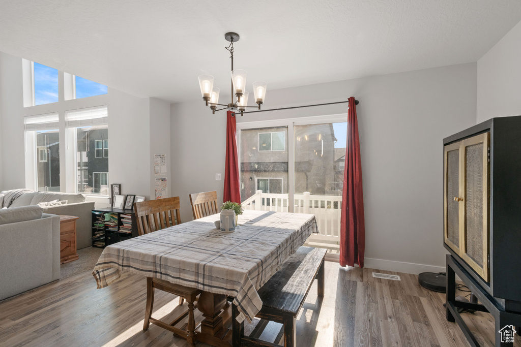 Dining space with a chandelier, healthy amount of natural light, and wood finished floors