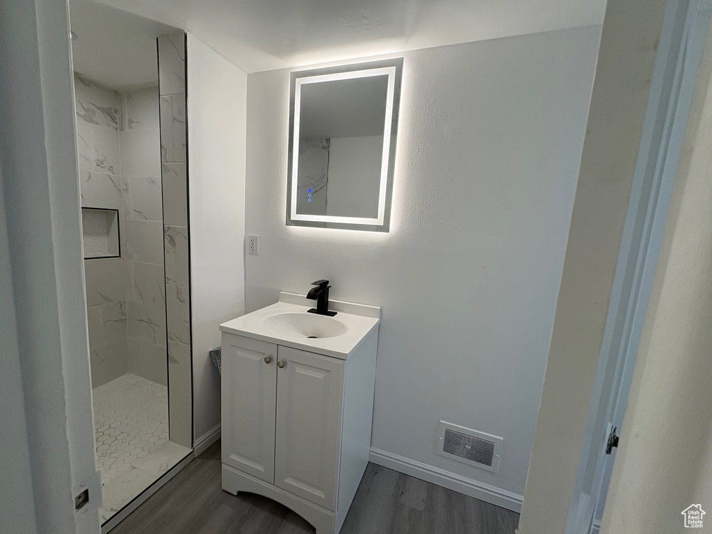 Bathroom with wood finished floors, a marble finish shower, and vanity