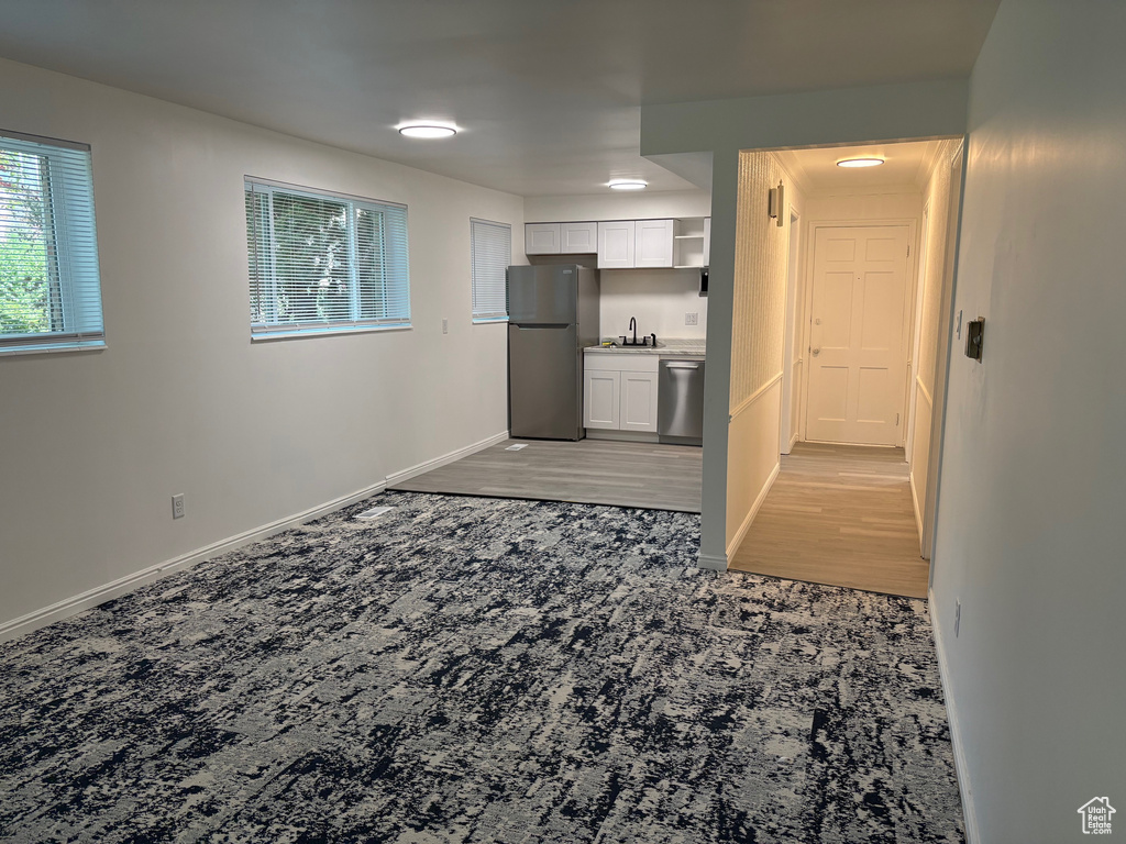 Kitchen with appliances with stainless steel finishes, white cabinets, and light carpet