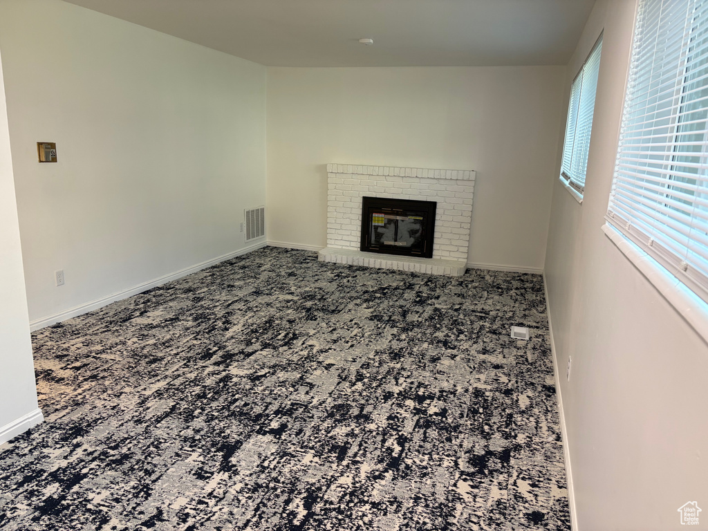 Unfurnished living room with carpet flooring and a fireplace