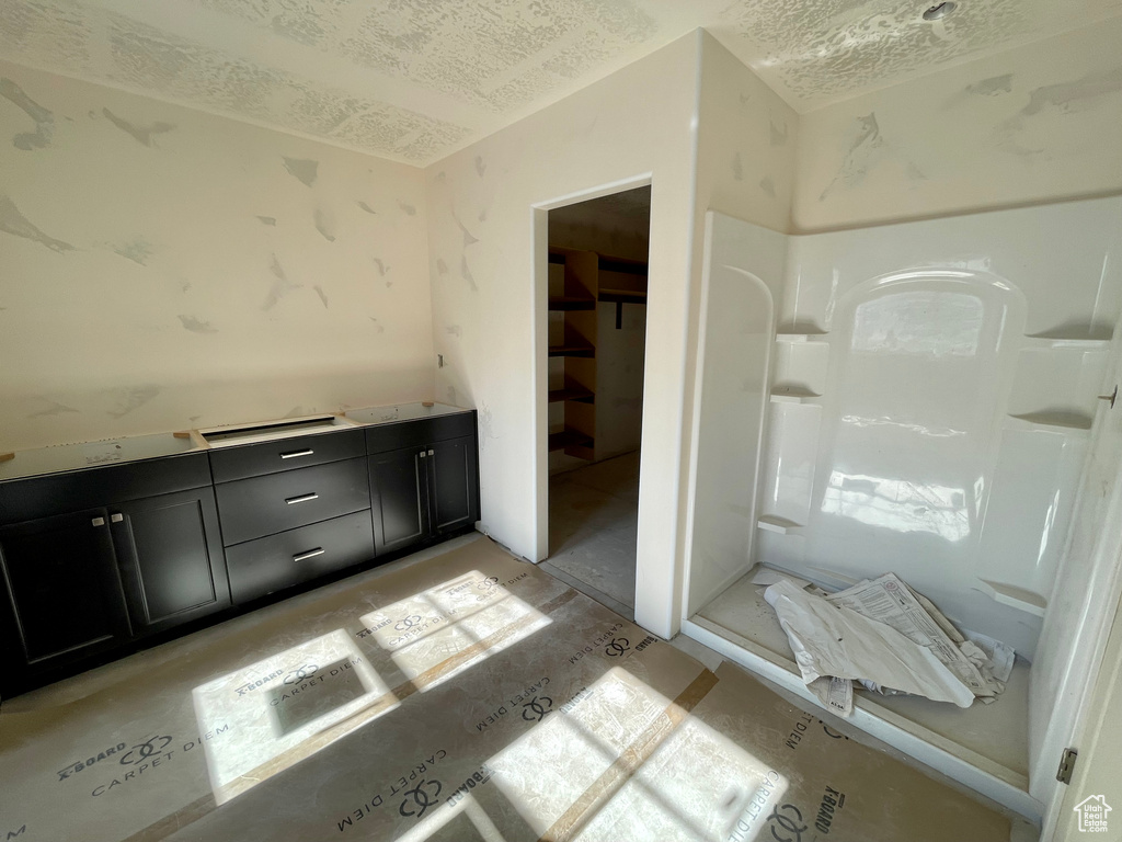 Bathroom featuring a textured ceiling and a walk in shower