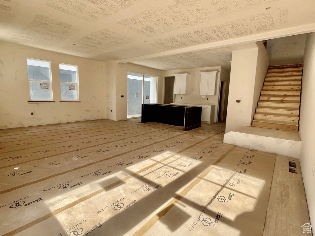 Unfurnished living room featuring stairs, healthy amount of natural light, and light wood finished floors
