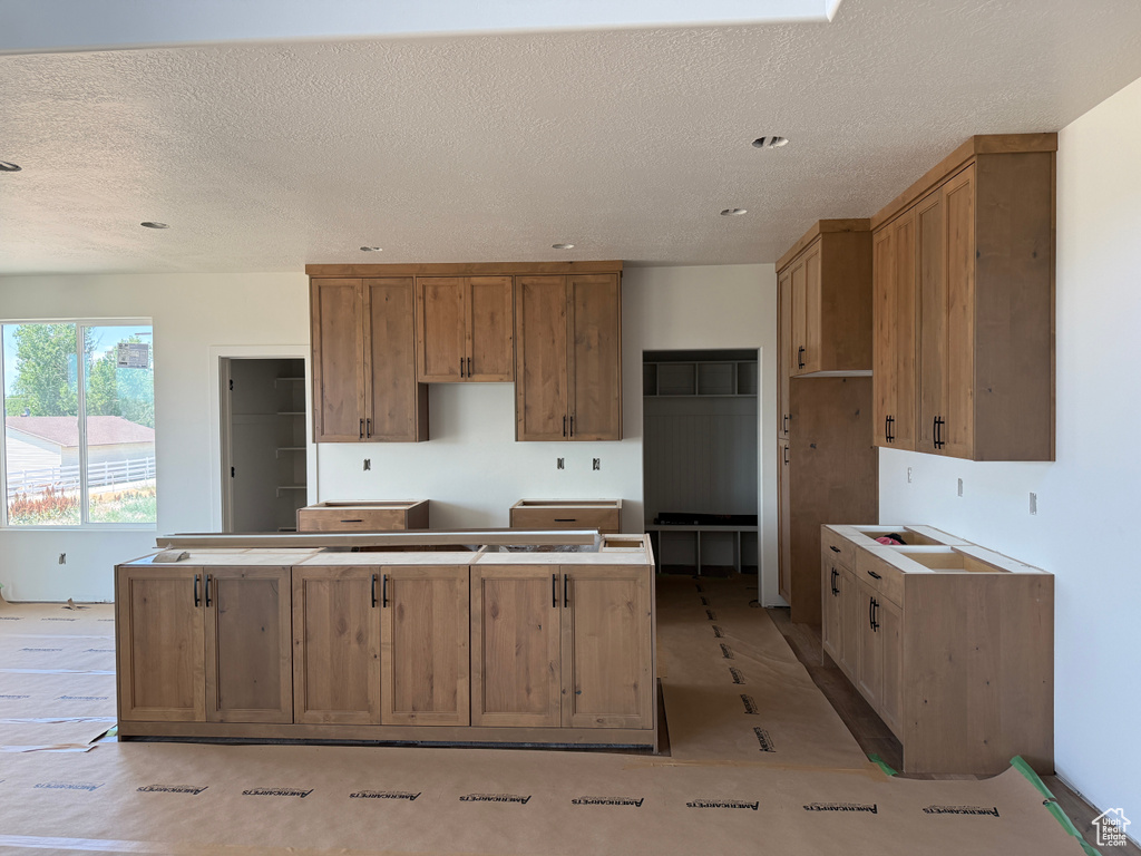 Kitchen featuring a kitchen island, a textured ceiling, and brown cabinetry
