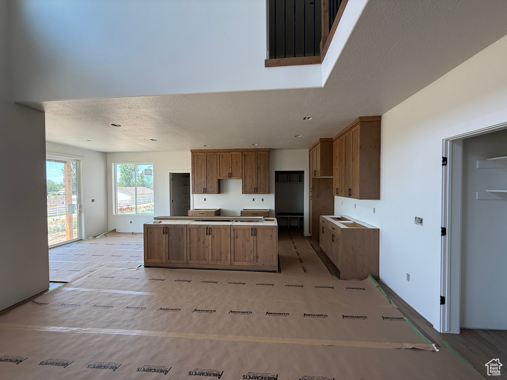 Kitchen featuring a center island, a textured ceiling, and brown cabinets