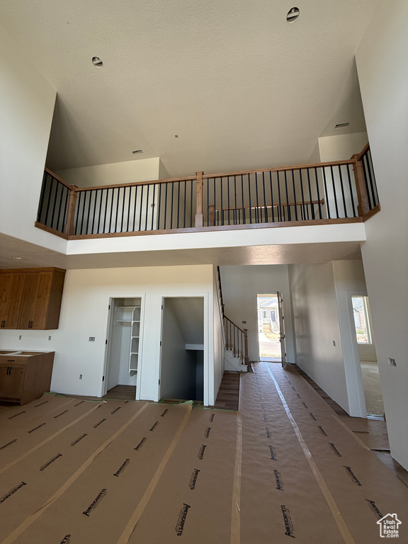Unfurnished living room featuring a towering ceiling, healthy amount of natural light, and stairway