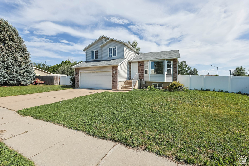Split level home with brick siding, driveway, a garage, and a shingled roof