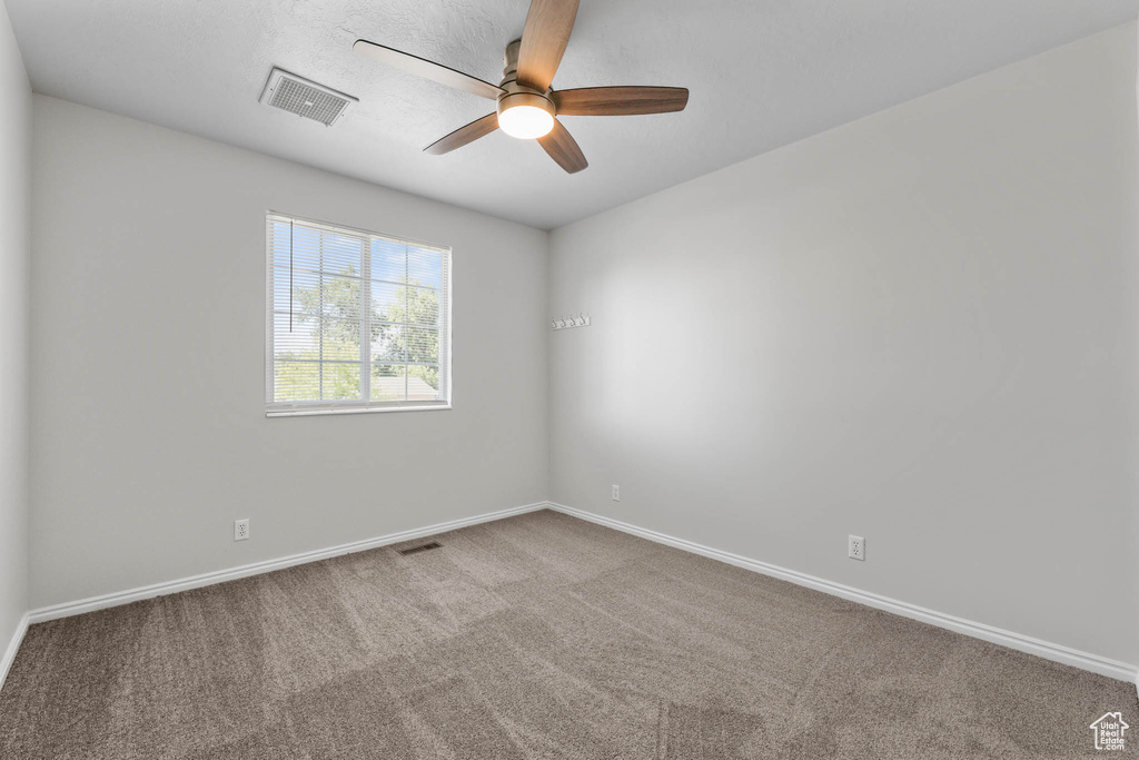 Carpeted empty room with a ceiling fan and baseboards