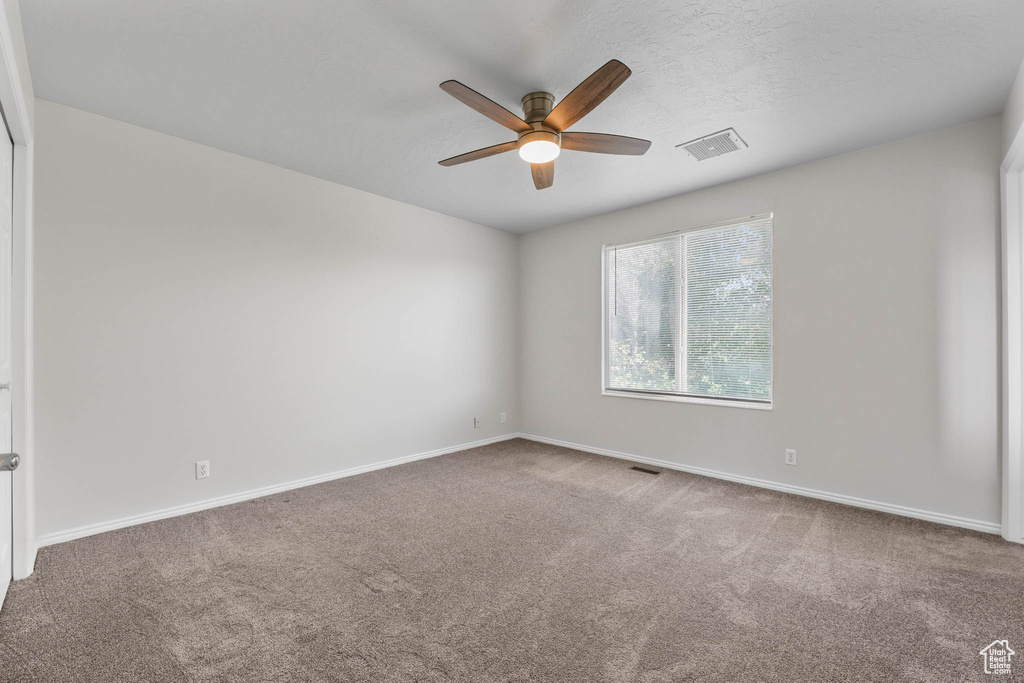 Carpeted spare room with ceiling fan and baseboards