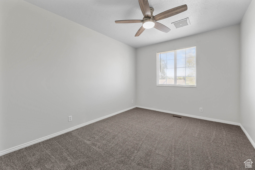Unfurnished room featuring a ceiling fan and dark colored carpet