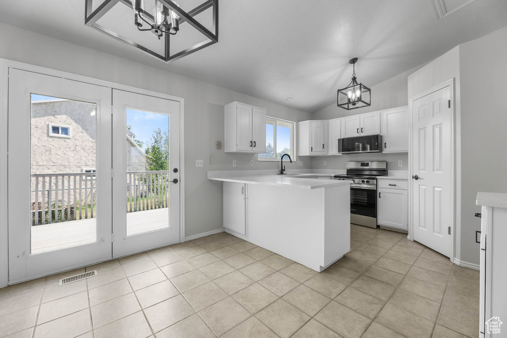 Kitchen with a chandelier, stainless steel range oven, black microwave, a peninsula, and light countertops