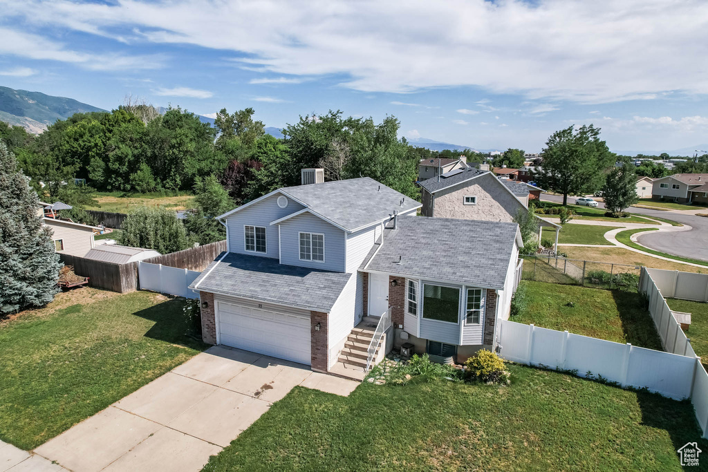 Traditional-style house featuring an attached garage, a chimney, driveway, brick siding, and a fenced backyard