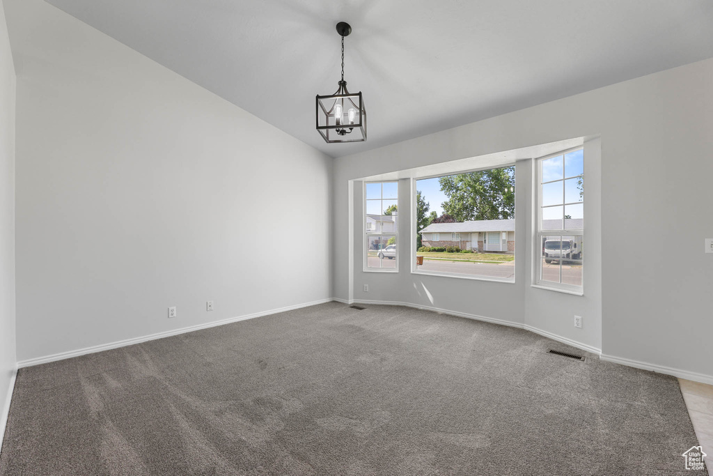 Unfurnished room featuring a chandelier, carpet flooring, and lofted ceiling