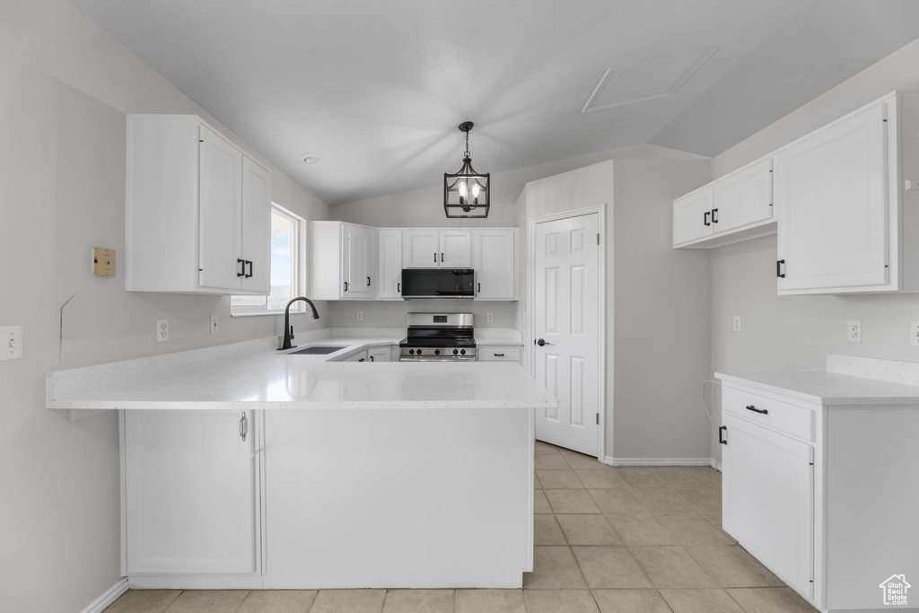 Kitchen featuring black microwave, stainless steel electric range oven, a peninsula, light countertops, and vaulted ceiling