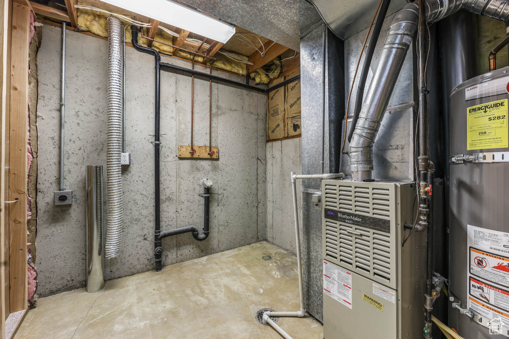 Utility room featuring strapped water heater and heating unit