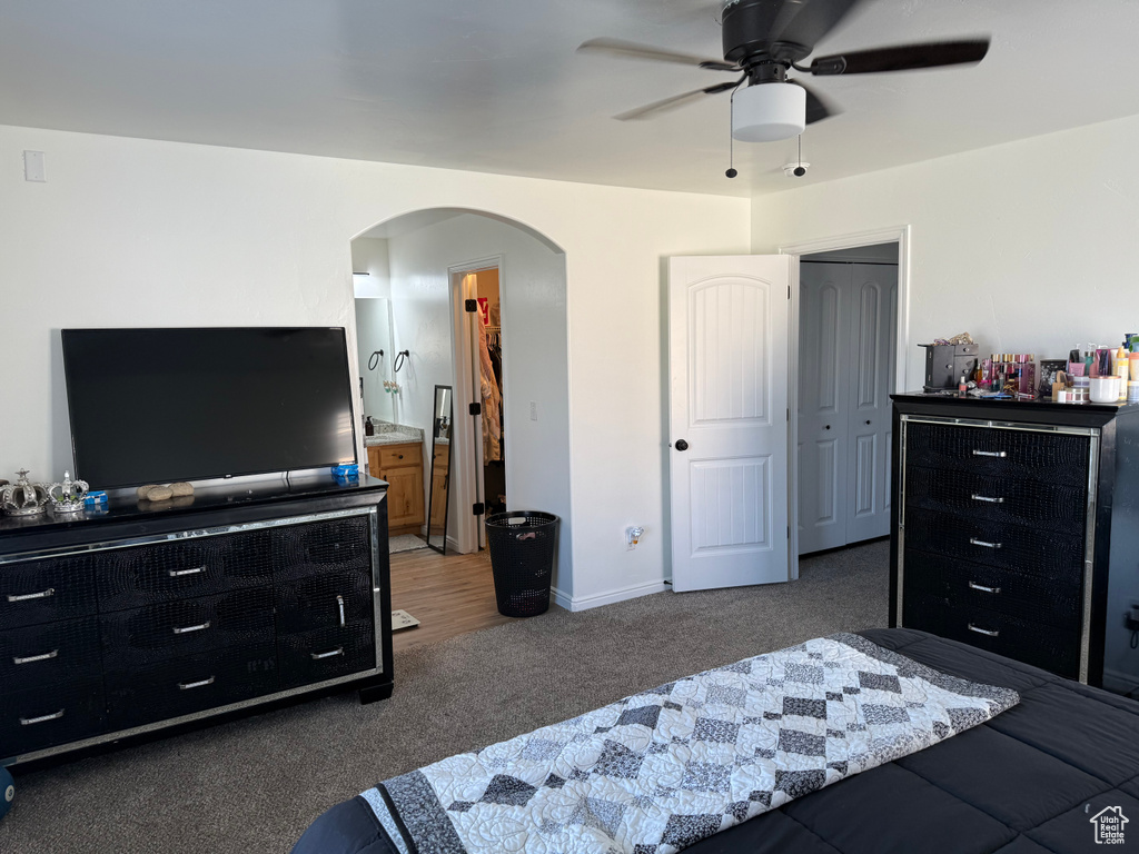 Carpeted bedroom with arched walkways, ceiling fan, and a closet