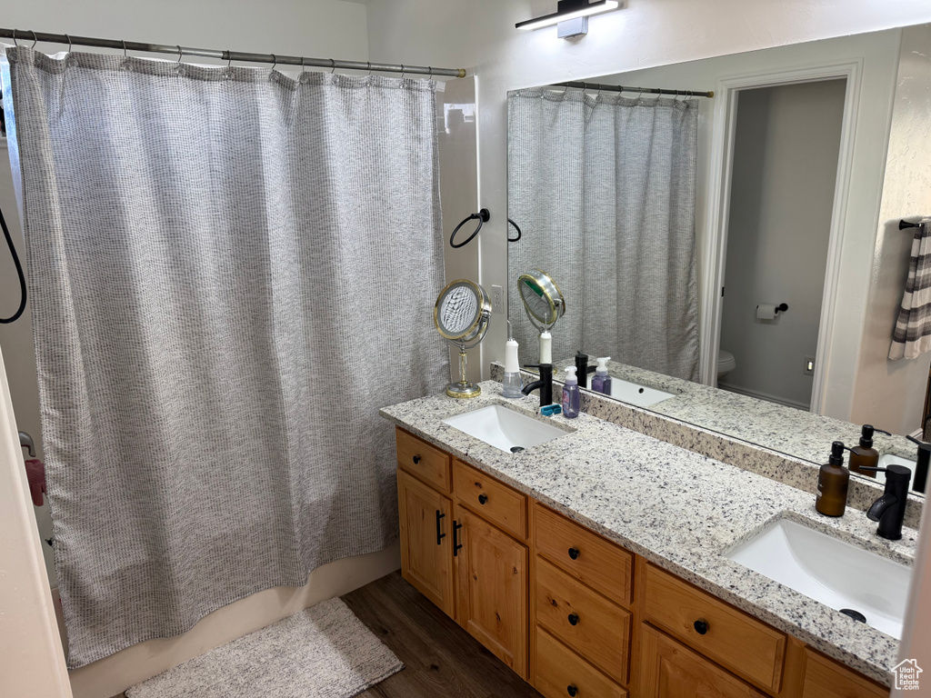 Full bath featuring wood finished floors, double vanity, and shower / bathtub combination with curtain
