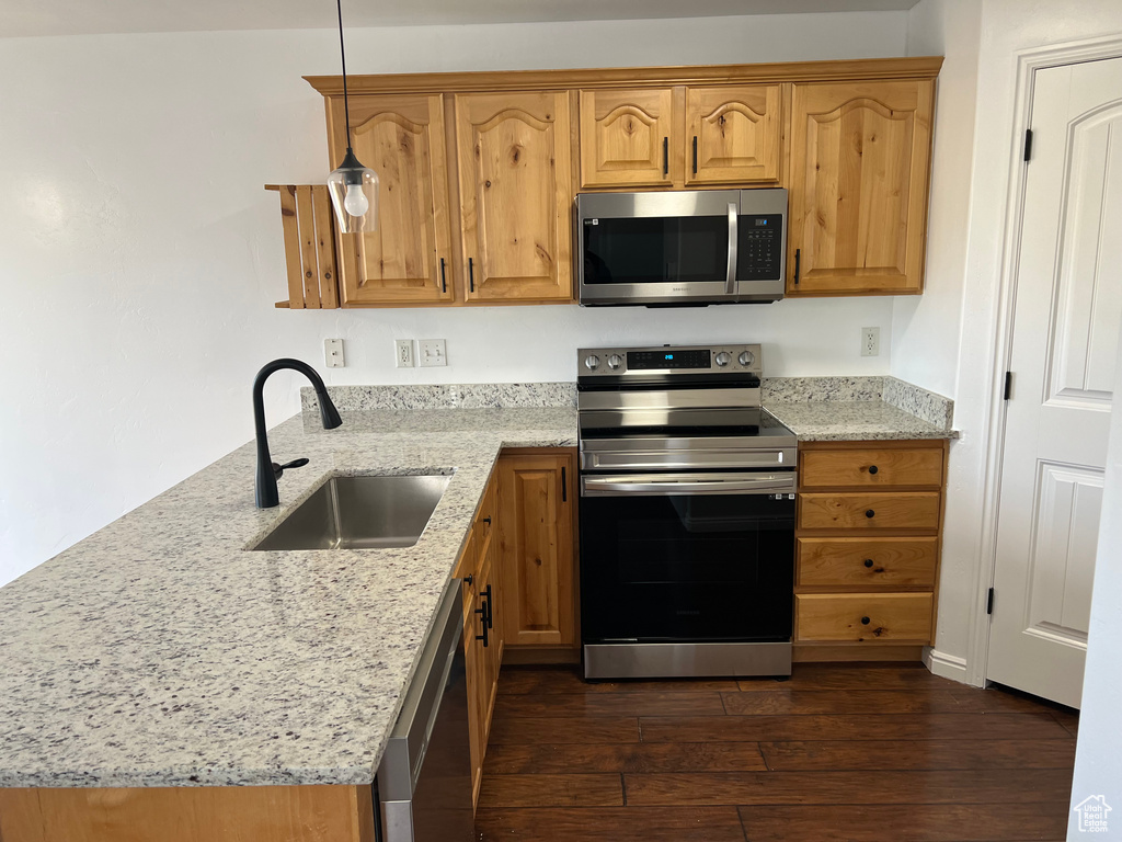 Kitchen with stainless steel appliances, dark wood finished floors, and light stone countertops