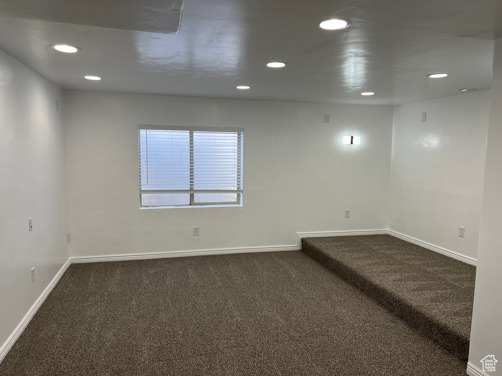 Empty room featuring dark colored carpet and recessed lighting