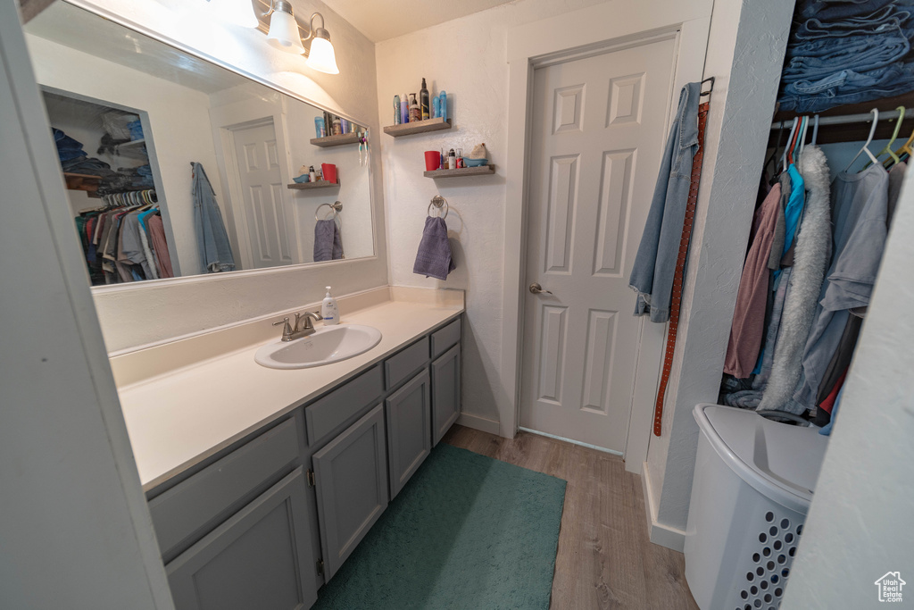 Full bath with wood finished floors, vanity, and a spacious closet