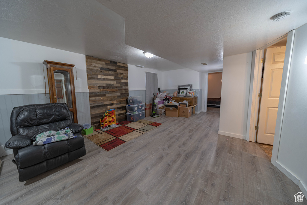 Sitting room with wood finished floors, a wainscoted wall, and a textured ceiling