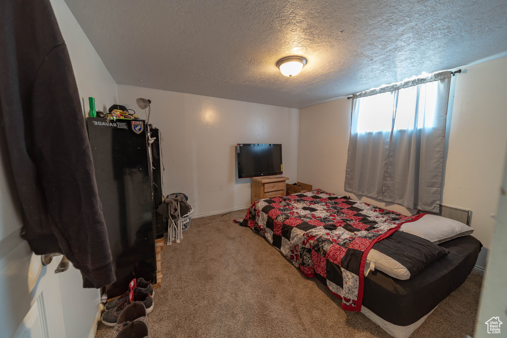 Carpeted bedroom with a textured ceiling and baseboards