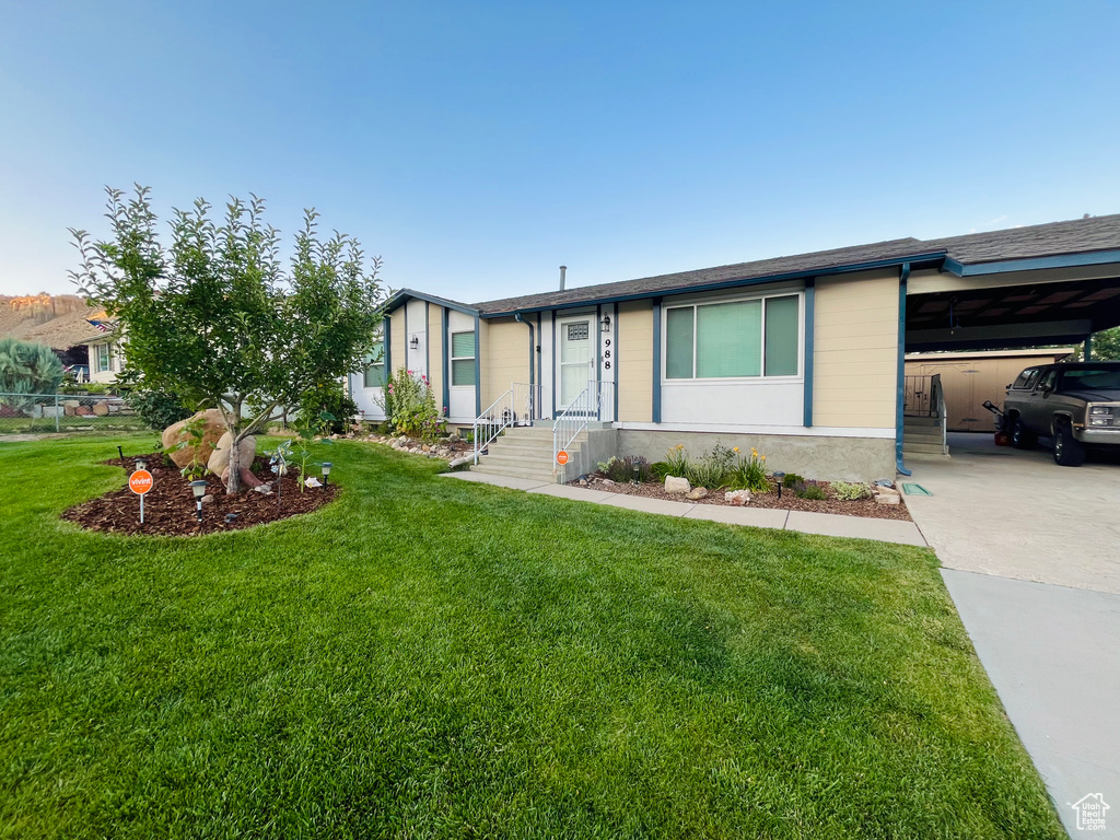 View of front of house featuring an attached carport, a front lawn, and driveway