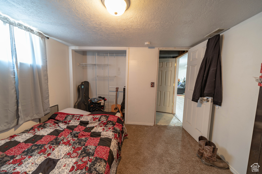 Carpeted bedroom featuring a textured ceiling and a closet